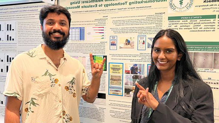 Two students posing in front of research posters
