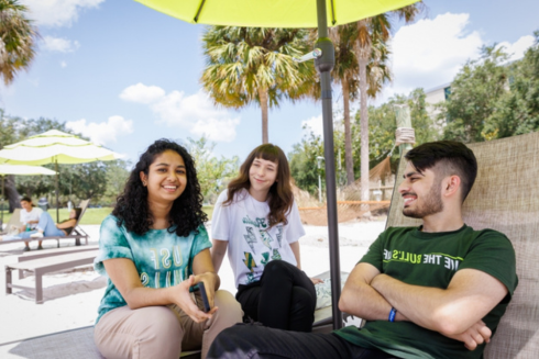 Three students sitting on 十大买球网站's beach on the Tampa campus, linking to Why 十大买球网站 webpage.